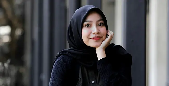 A woman wearing a hijab and resting her chin in her hand. 