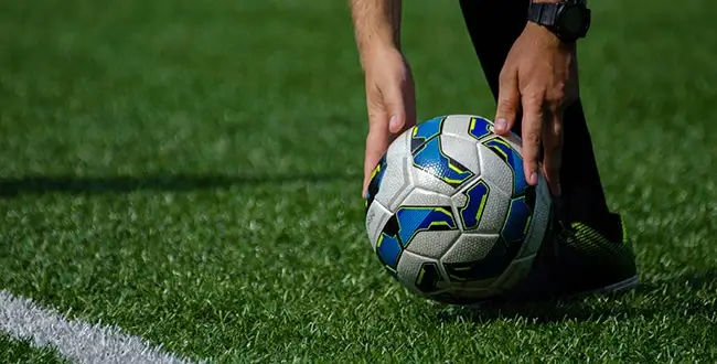 Athlete placing soccer ball on field